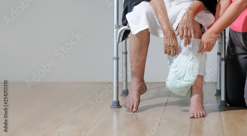 elderly woman changing diaper with caregiver