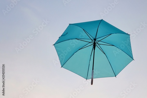 blue umbrella floating on the air, isolate on sky background, sunset