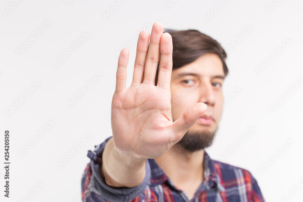 People, expression and gesture concept - young man showing stop gesture on white background People, expression and gesture concept - young man showing stop gesture on white background