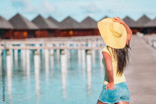 Woman with yellow hat relaxing at swimming pool in exotic resort