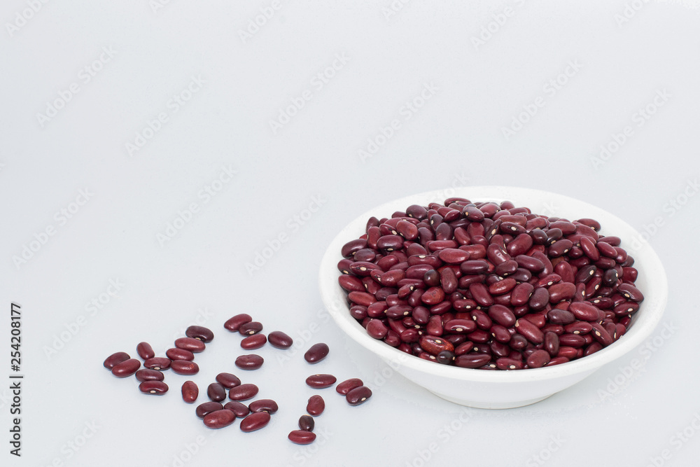 Grains of red beans in a white plate on a gray background