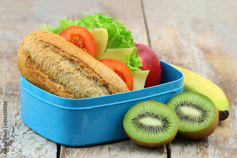 Healthy school lunch box containing brown cheese roll apple banana and kiwi fruit Stock Foto Adobe Stock