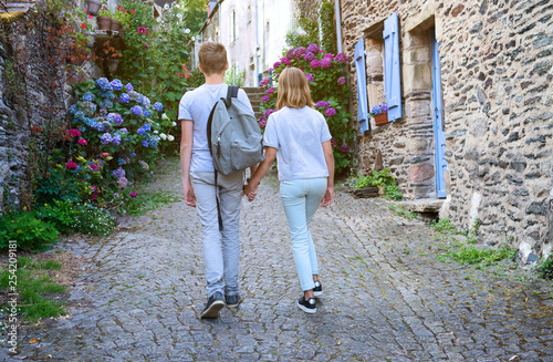Fototapeta Naklejka Na Ścianę i Meble -  Old villge in Europe with blossom bushes of hydrangea. Teenagers people and travel concept. Teens walking in the streets of old town.