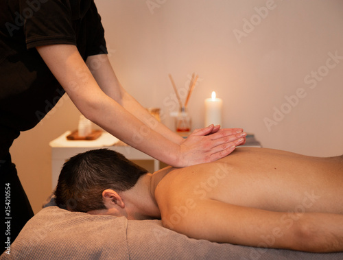 Man getting a massage by a woman in warm environments. Spa and wellness.