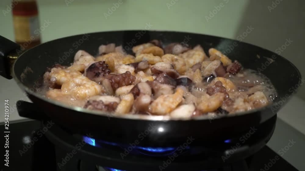 Pouring seafood stewed in a frying pan with sauce. Pouring seafood stewed in a frying pan with sauce.