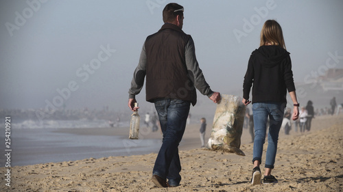 Man and his daughter cleaning the beach