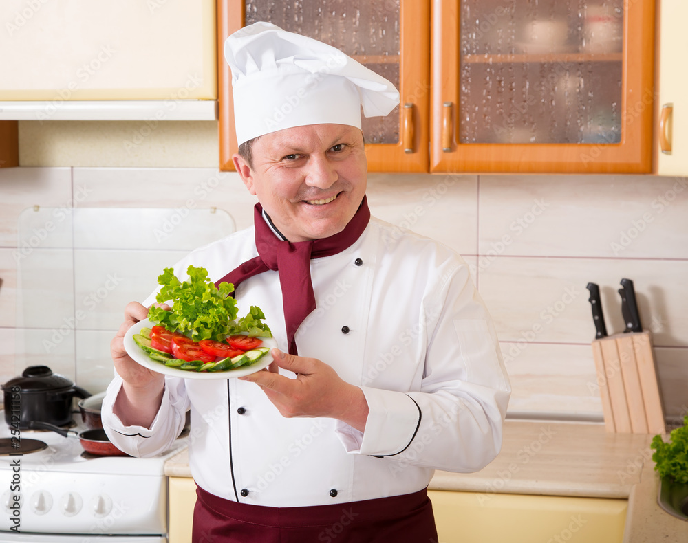 Mature male cook prepared vegetable salad in the kitchen. Man chef knows the cooking recipes. Mature male cook prepared vegetable salad in the kitchen. Man chef knows the cooking recipes.