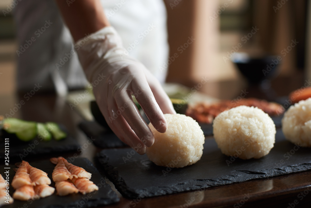 Close-up view of process of cooking rolling sushi at restaurant . Chef is preparing ingredients for rolls