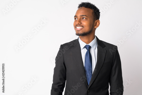 Happy young handsome African businessman in suit thinking