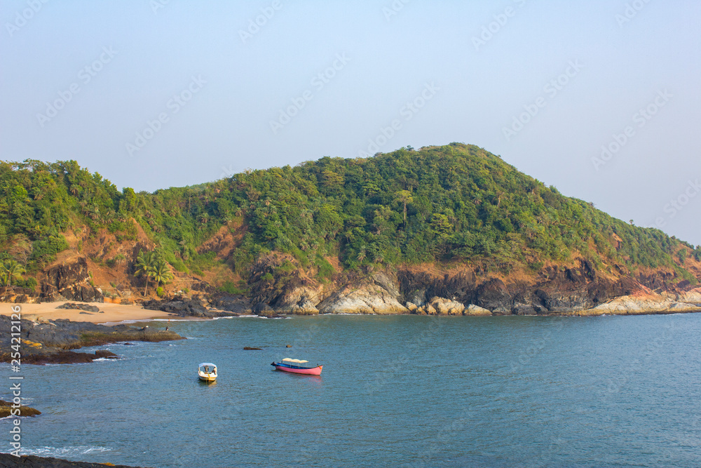 blue bay with boats on the water on the background of a green rocky hill