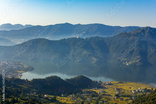 Phewa lake and Pokhara town in a green mountain valley with fog. Aerial view.