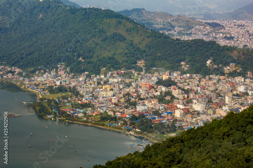 view of the city of Pokhara near the lake Phewa with boats on the water, against the background of the city of the green mountain valley aerial view