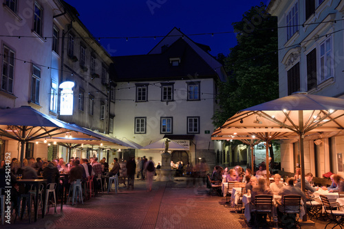 Nightlife outdoor restaurant cafes in Cobblestone Courtyard Ribji or Fish Square from Cankar Quay to Town Square in Old Town Ljubljana Slovenia © Reimar