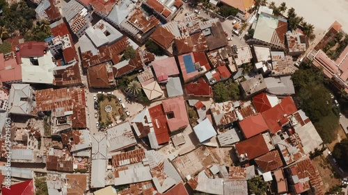 Bird's eye view of Stone Town buildings roofs, coastline, beach, and anchored fishing boats on a sunny day photo