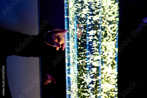 therapy sensory stimulating multi sensory room, woman interacting with colored lights bubble tube lamp during therapy session