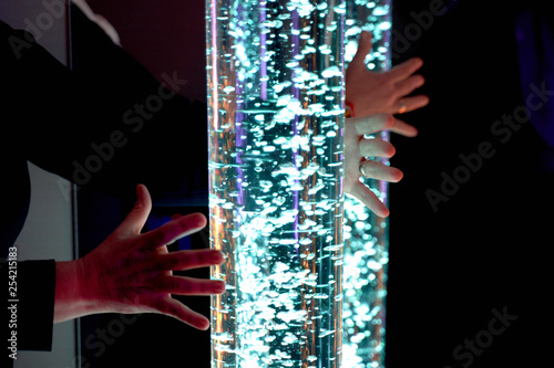 therapy sensory stimulating multi sensory room, woman interacting with colored lights bubble tube lamp during therapy session