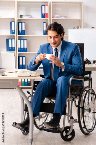 Male employee in wheelchair working at the office 