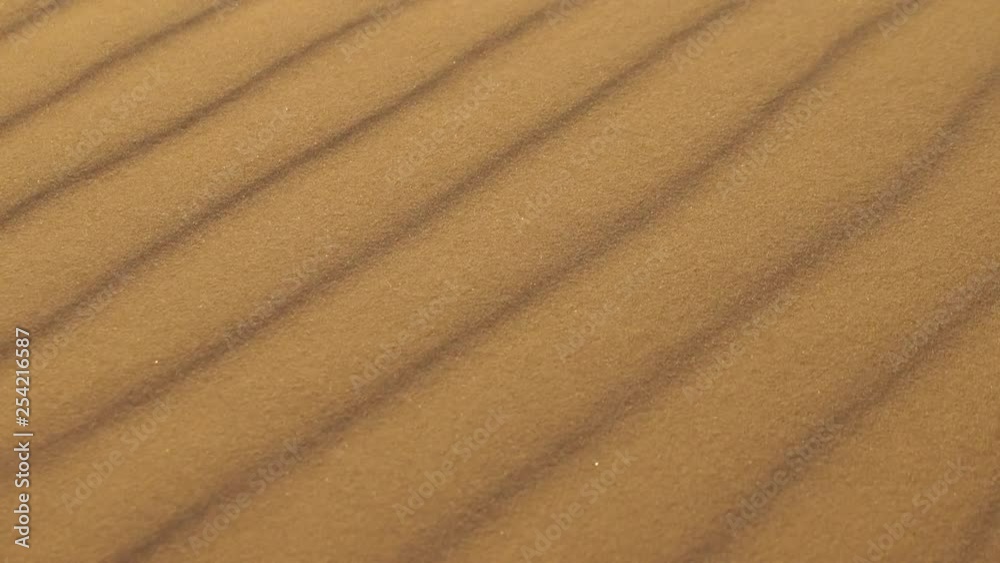 Wind blowing desert sand dune patterns close up with sparkles and glistening particles Wind blowing desert sand dune patterns close up with sparkles and glistening particles