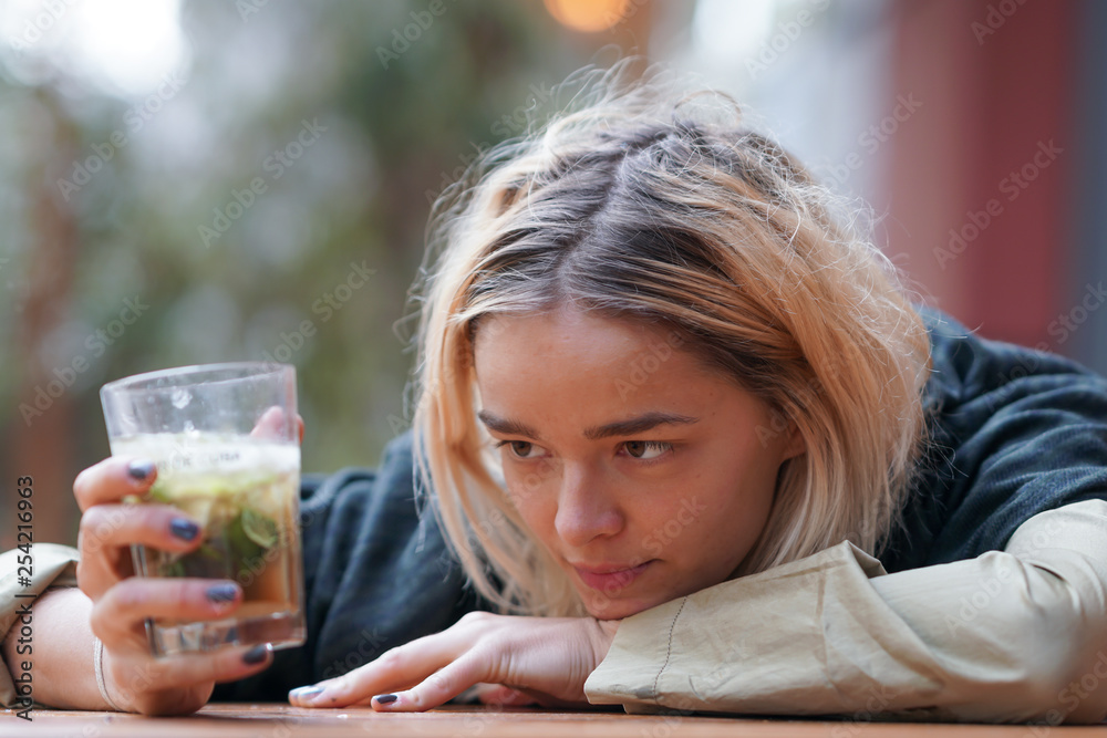 Sad looking woman holding a drink on the table Sad looking woman holding a drink on the table