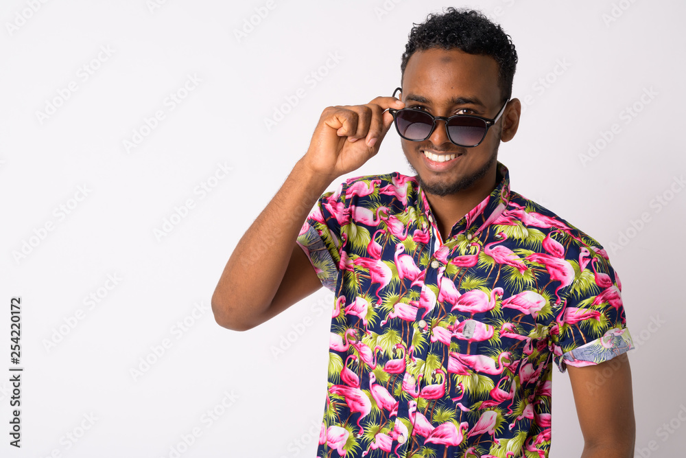 Happy young handsome African tourist man peeking through sunglasses Happy young handsome African tourist man peeking through sunglasses
