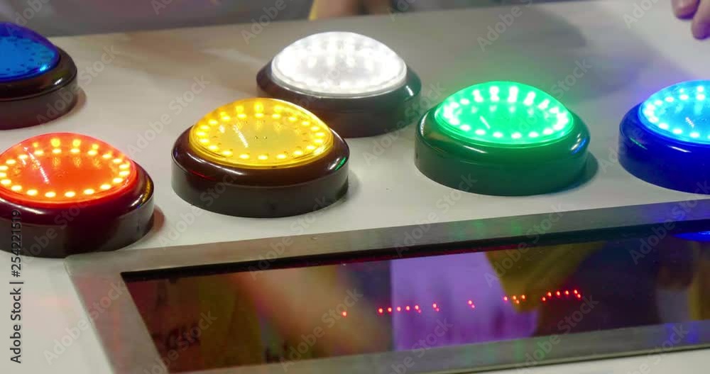 Close up of kids playing on reflex testing machine with colourful lights to hit.