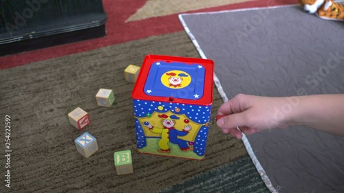 A woman's hand winding a jack-in-the-box toy until it pops up. Shot in slow motion
