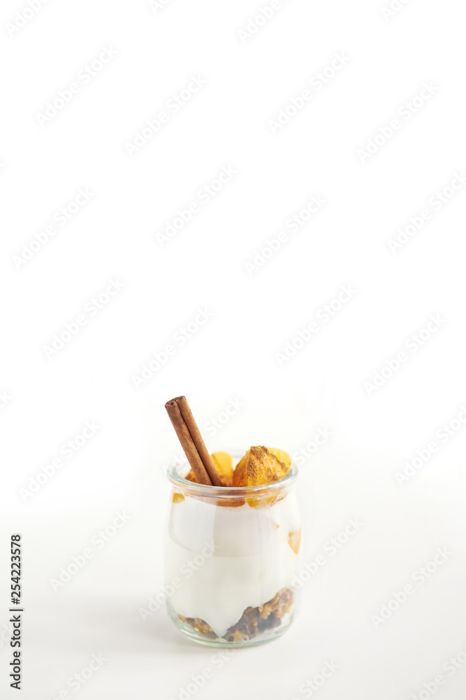Jars of greek yogurt with granola, cinnamon and canned apricots on white background, copy space, vertical oriented Jars of greek yogurt with granola, cinnamon and canned apricots on white background, copy space, vertical oriented
