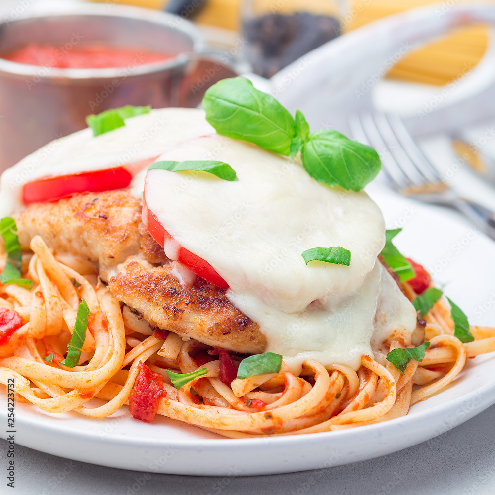 Chicken caprese with tomato and mozzarella cheese, served with linguine, tomato pasta sauce and basil, square, closeup Chicken caprese with tomato and mozzarella cheese, served with linguine, tomato pasta sauce and basil, square, closeup