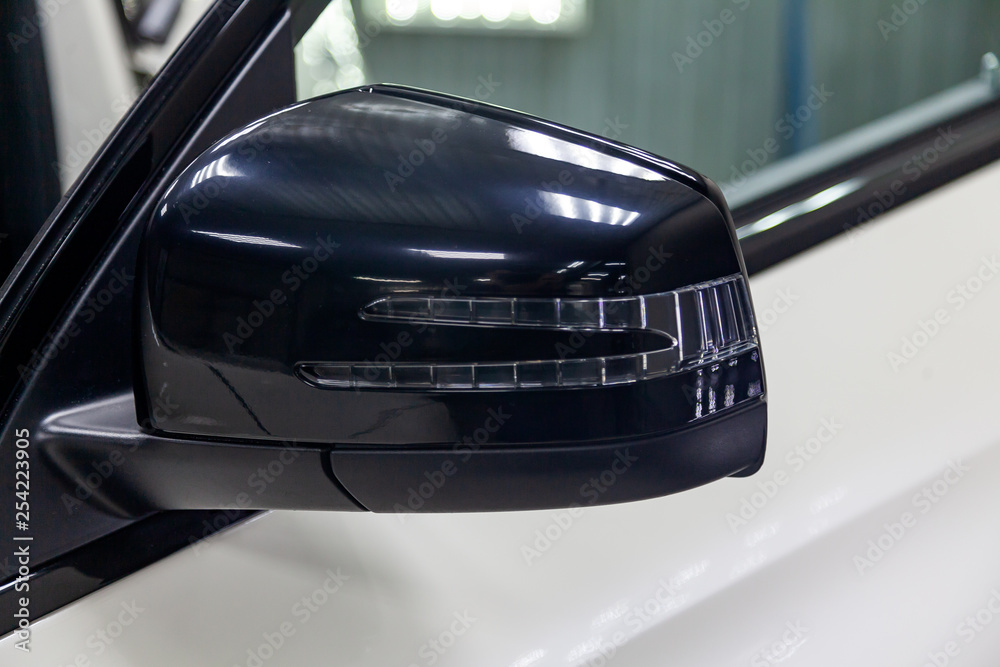 Close-up of the black side mirror of the car body in the design of a white suv with turn light