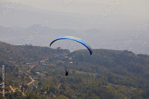 Flying on a paraglider. Beautiful view with mountains and colorful paragliders. Extreme vacation travel
