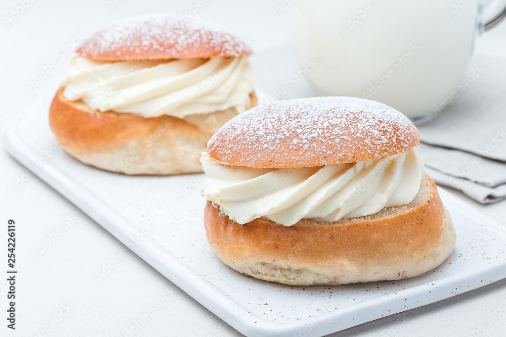 Traditional swedish dessert Semla, also called Shrove bun, with almond paste and whipped cream filling, served with milk, horizontal Traditional swedish dessert Semla, also called Shrove bun, with almond paste and whipped cream filling, served with milk, horizontal