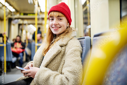 junge Frau, Mädchen, Teenager, sitzt mit ihrem Smartphone, Handy, in der U-Bahn photo