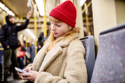 junge Frau, Mädchen, Teenager, sitzt mit ihrem Smartphone, Handy, in der U-Bahn photo