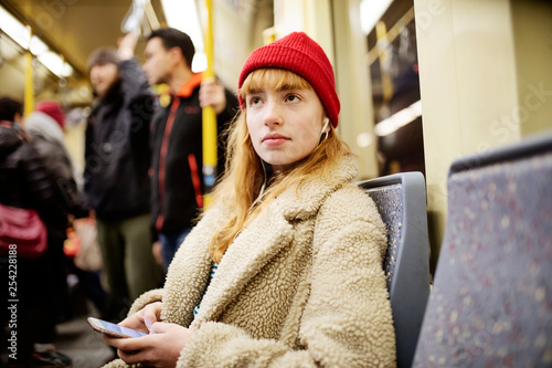 junge Frau, Mädchen, Teenager, sitzt mit ihrem Smartphone, Handy, in der U-Bahn photo