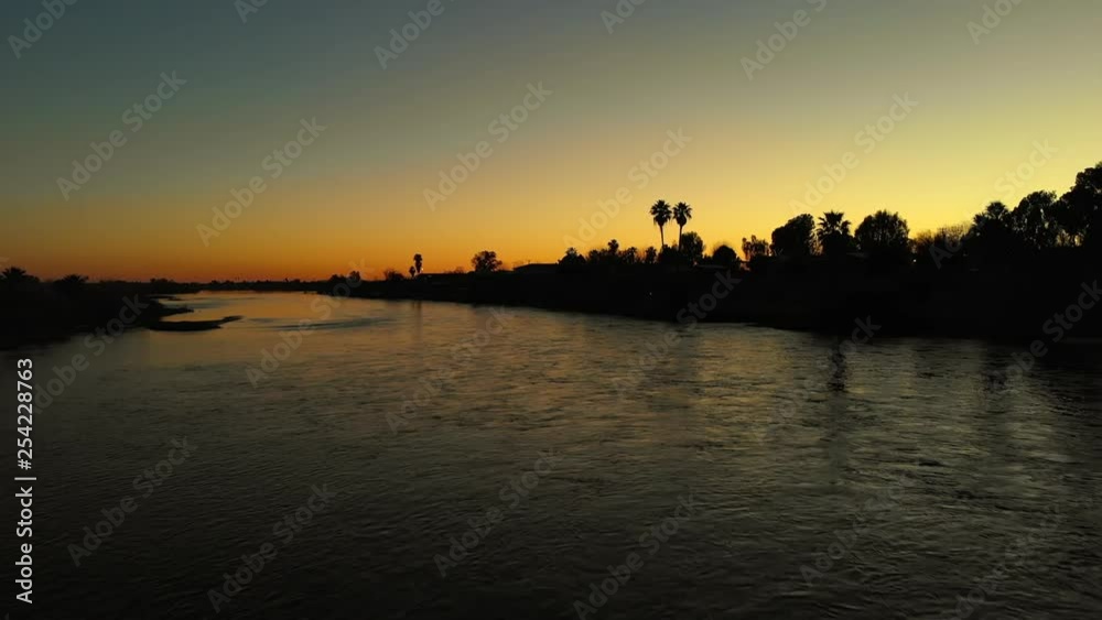 Cinematic Sunset Along The River Water From A Low Drone Viewpoint With Palm Trees And A Bird Flying By Cinematic Sunset Along The River Water From A Low Drone Viewpoint With Palm Trees And A Bird Flying By