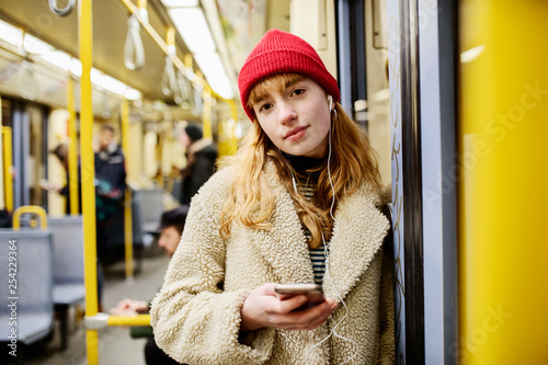 junge Frau, Teenager, Mädchen fährt mit ihrem Smartphone in der Hand U-Bahn photo