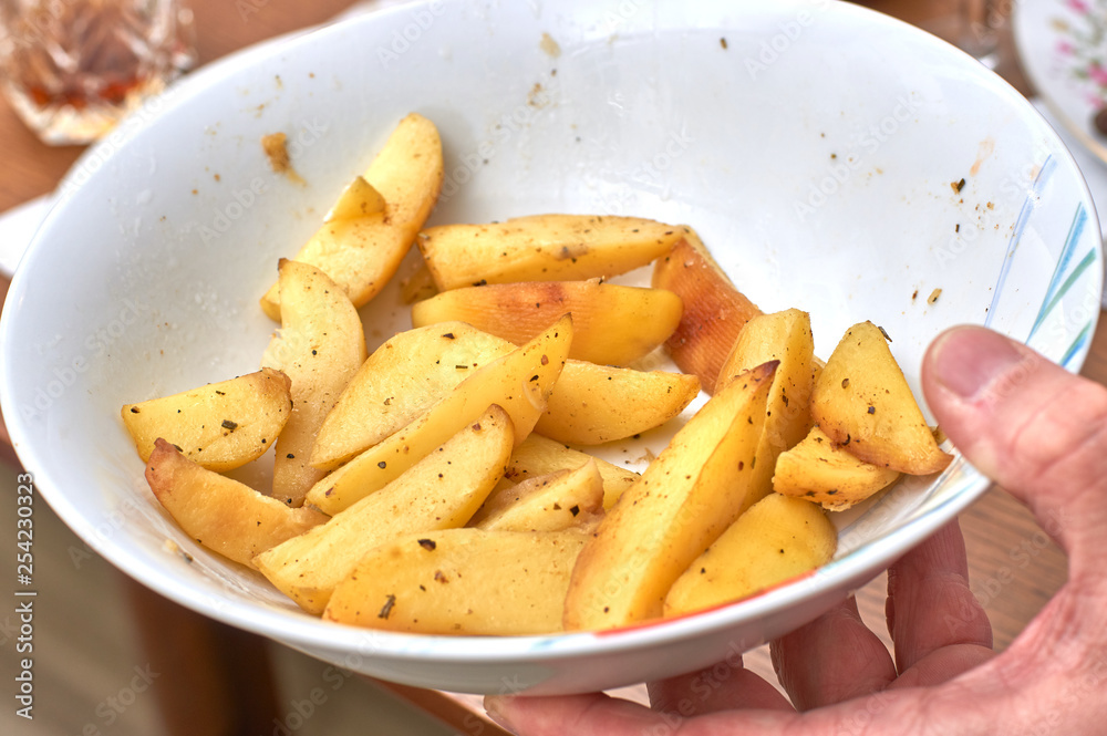 A hand holds a plate with remnants of hot idaho fried potatoes A hand holds a plate with remnants of hot idaho fried potatoes