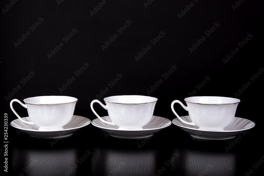 Three white tea cups stand on a table on a black background Three white tea cups stand on a table on a black background