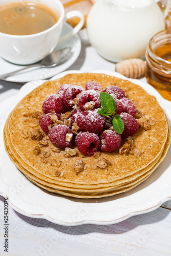 traditional sweet pancakes with fresh raspberries for breakfast on wooden table, vertical