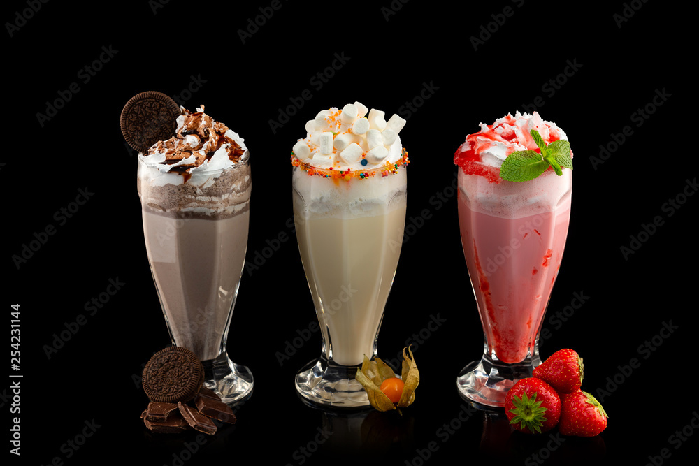 symmetri kollision øge Three glasses of colorful milkshake cocktails - chocolate, strawberry and  vanilla decorated with fresh berries and mint isolated at black background.  Stock Photo | Adobe Stock