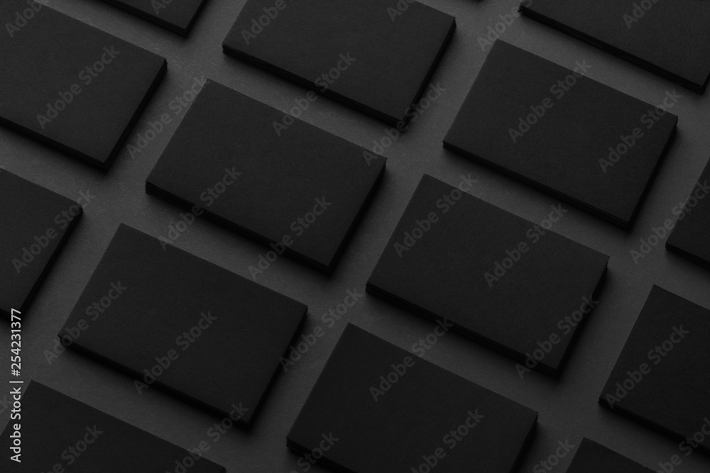 Mockup of horizontal business cards stacks arranged in rows at black textured paper background. Mockup of horizontal business cards stacks arranged in rows at black textured paper background.