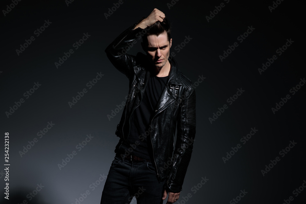 fashion young man in leather jacket pulls his hair up