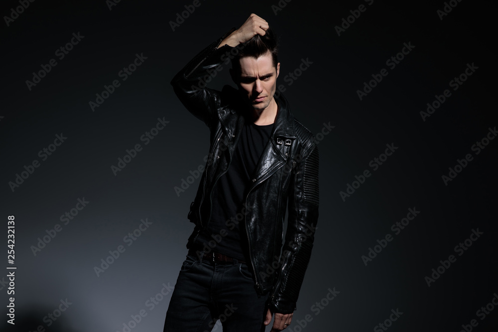 fashion young man in leather jacket pulls his hair up fashion young man in leather jacket pulls his hair up