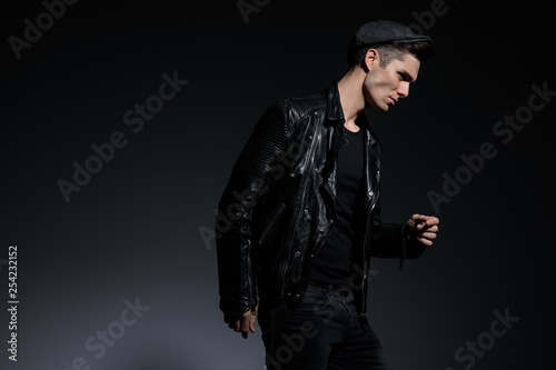 curious fashion man in leather jacket walks and looks away