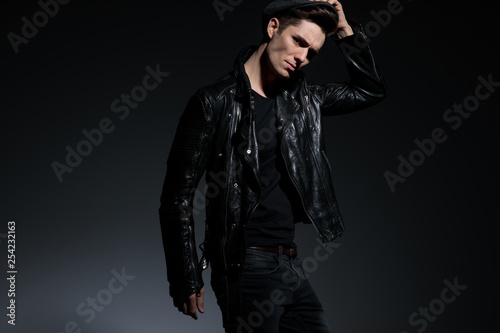 angry fashion man in leather jacket holding his hat