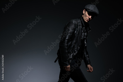 dramatic young man in leather jacket walks and leans forward