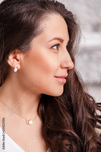 Closeup cute beautiful brunette girl with long hair in silver jewelry earrings and necklace. Сoncept of gentle, elegant, delicate, romantic jewelry, bijouterie on the model