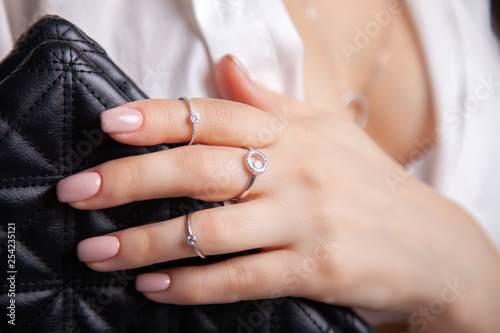 Closeup beautiful brunette girl with long hair in silver jewelry earrings, rings, bracelet and necklace in decollete. Сoncept gentle, elegant, delicate, romantic jewelry, bijouterie on model