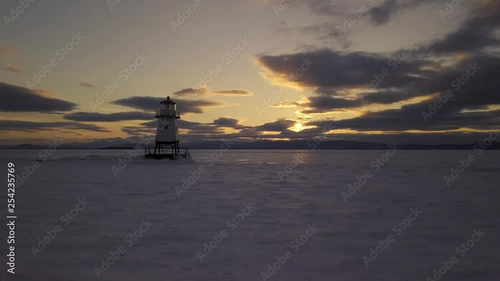 Drone flying by lighthouse on frozen lake at sunset. Drone flying by lighthouse on frozen lake at sunset.