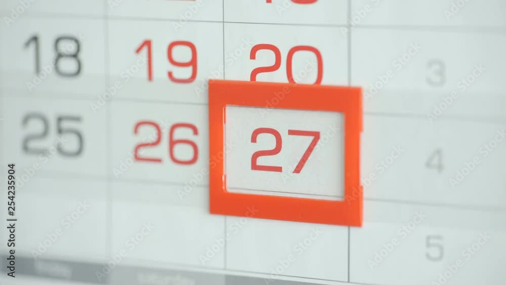 Woman's hand in office changes date at wall calendar. Changes 26 to 27 Woman's hand in office changes date at wall calendar. Changes 26 to 27